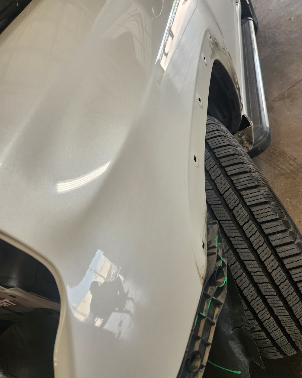A pale pearl fender and wheel arch with a long unbroken highlight running down the crown of the panel.
